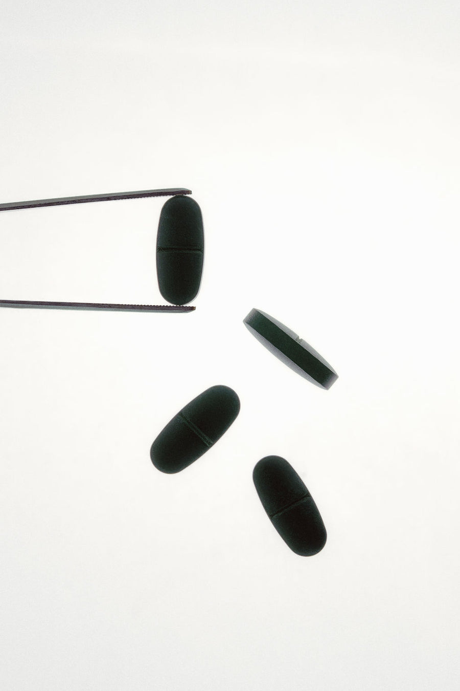 Green supplement pills scattered across back lit studio